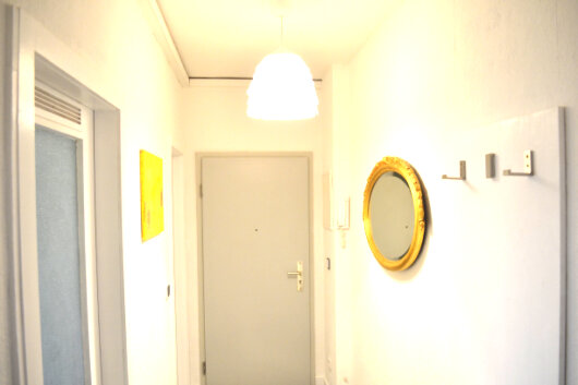 Kleiner Flur mit rundem goldenen Spiegel und Garderobenbügel