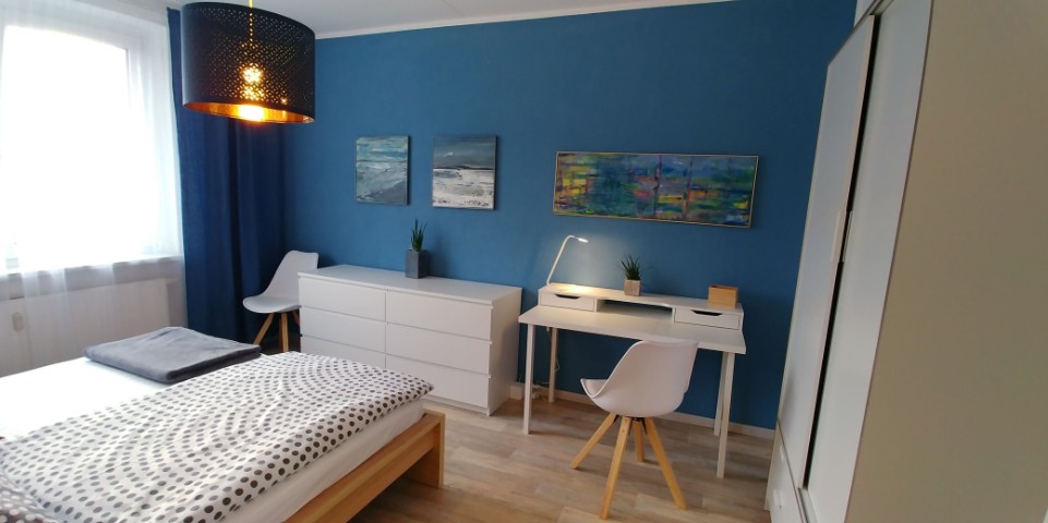 Schlafzimmer der Ferienwohnung in Leuben mit blauem Akzent und Arbeitsbereich